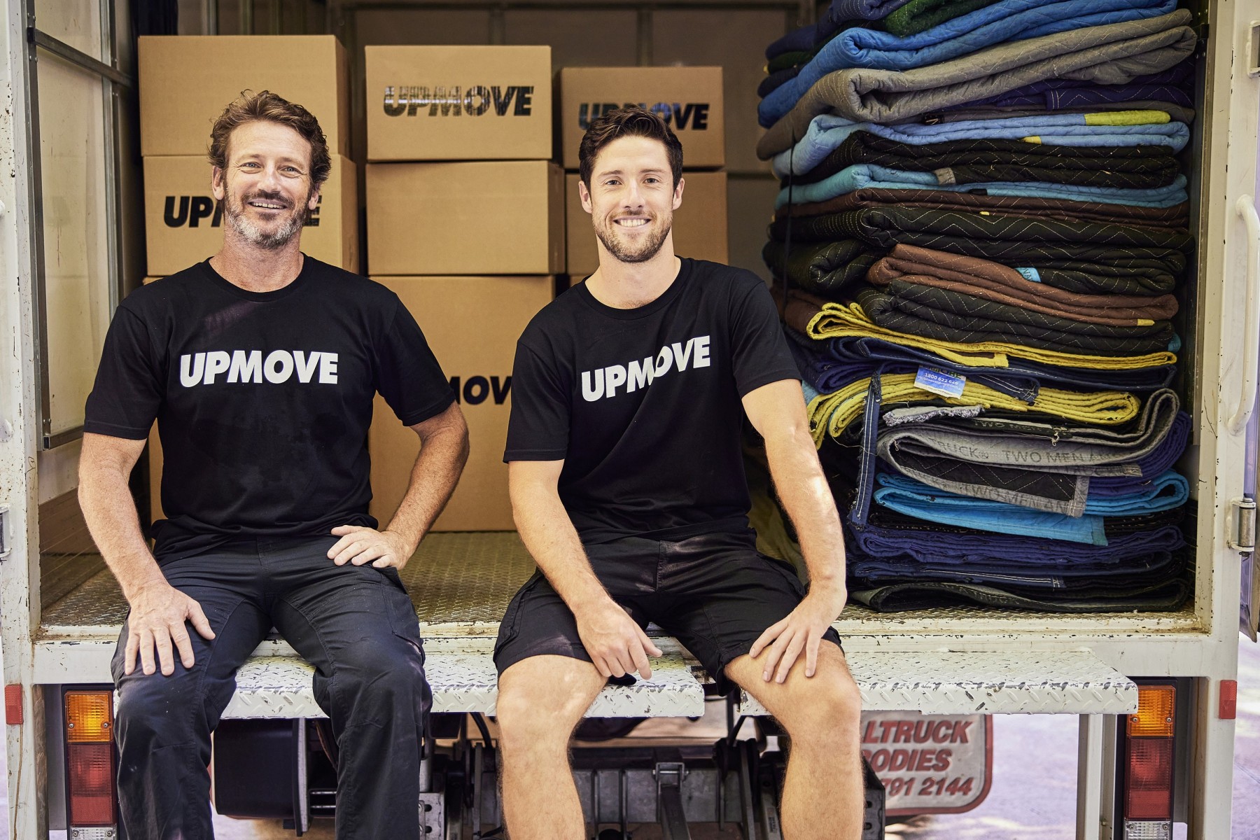 2 removalists sitting in the back of a truck
