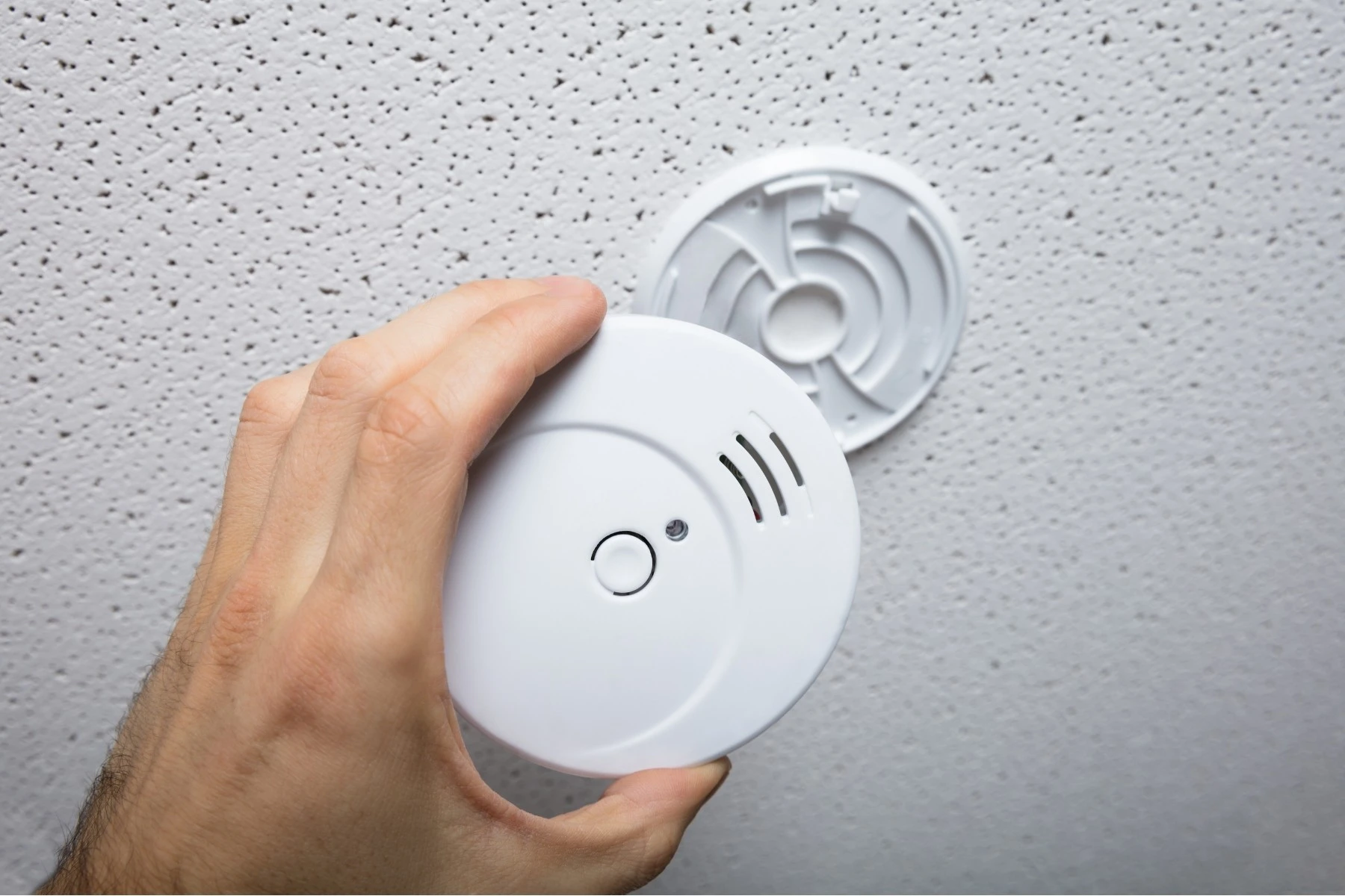 “Electrician testing ceiling smoke alarm in new home