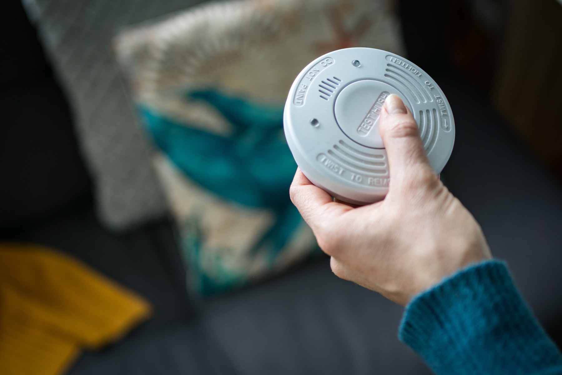 Hand holding a smoke alarm in a Australian home