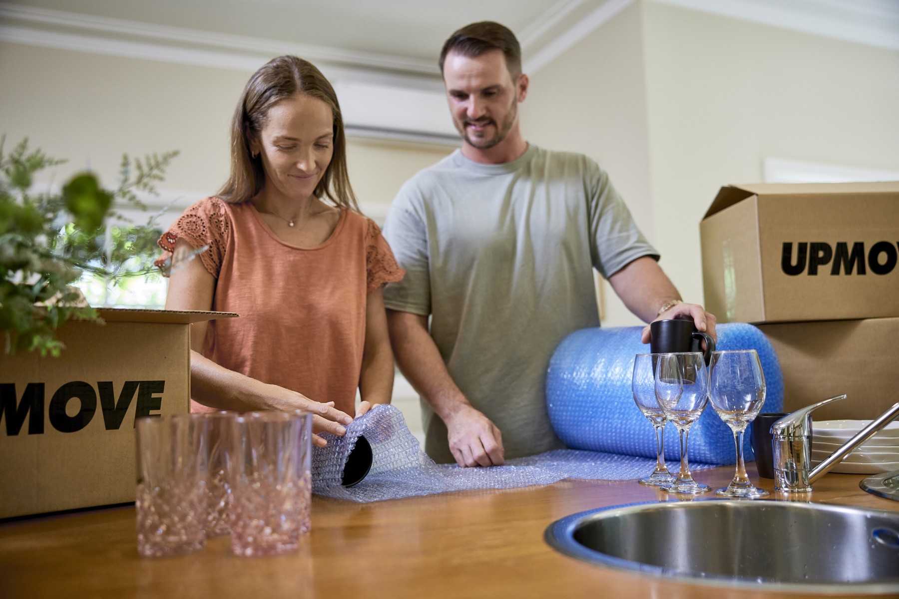 couple wrapping glasses in bubble wrap