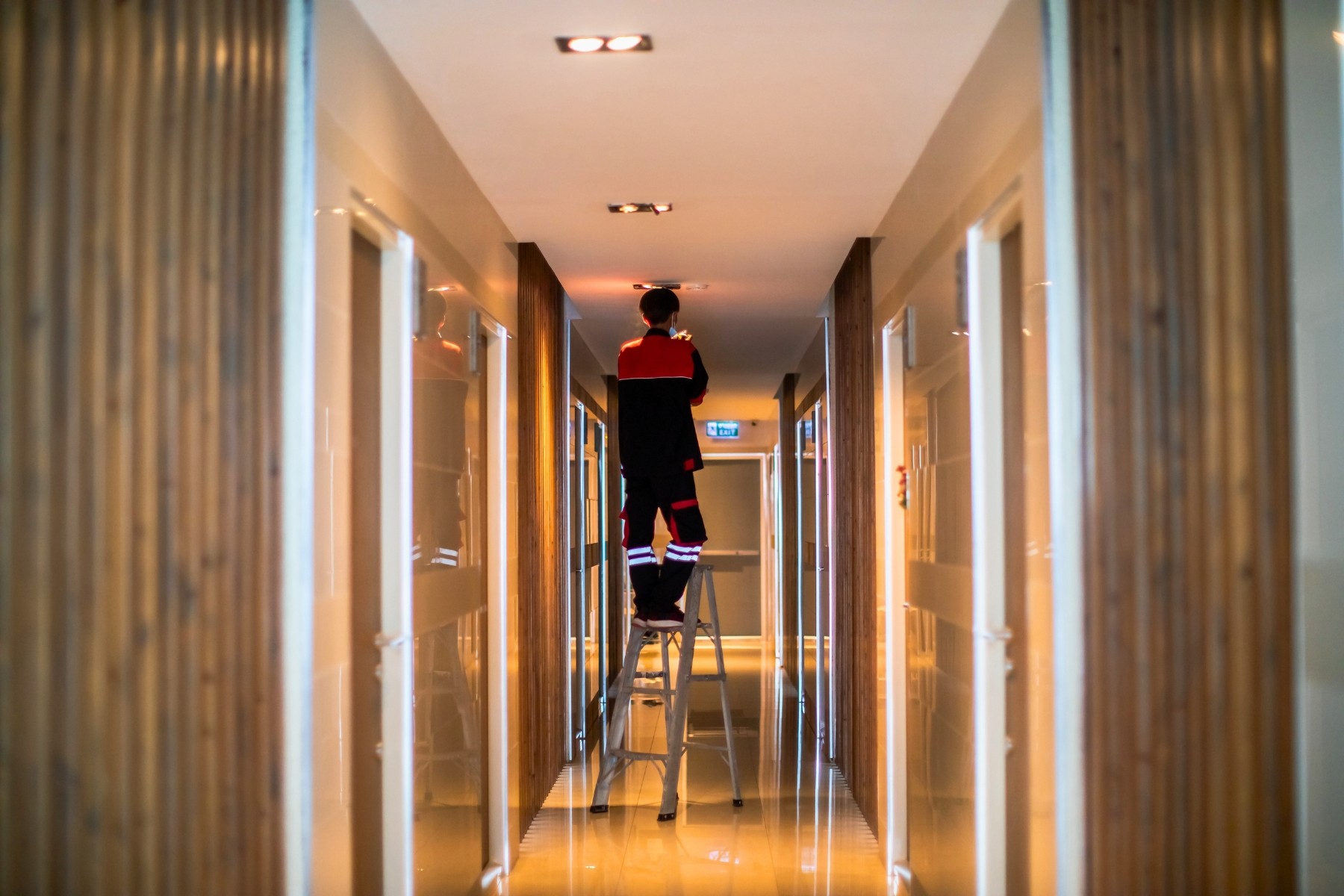 Technician installing smoke alarm on ceiling of residential building