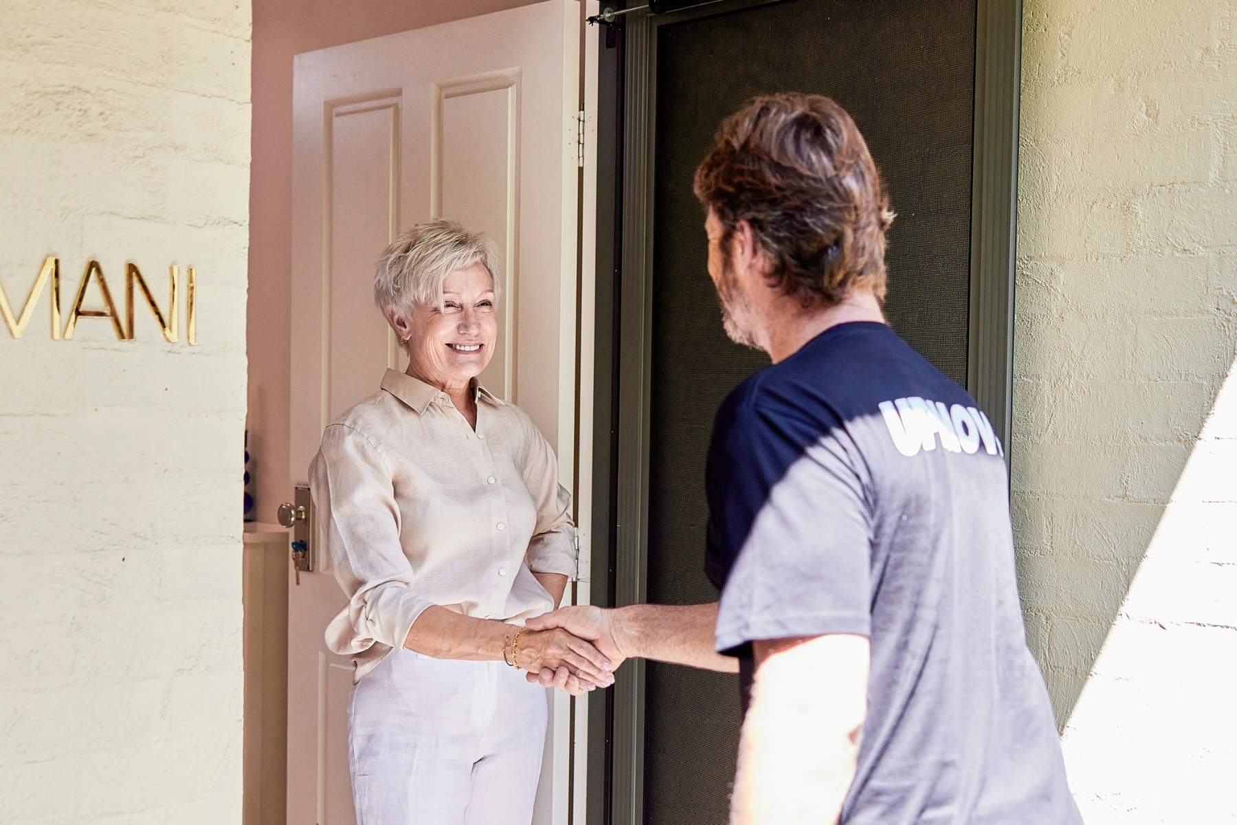 woman at front door shaking removalist's hand