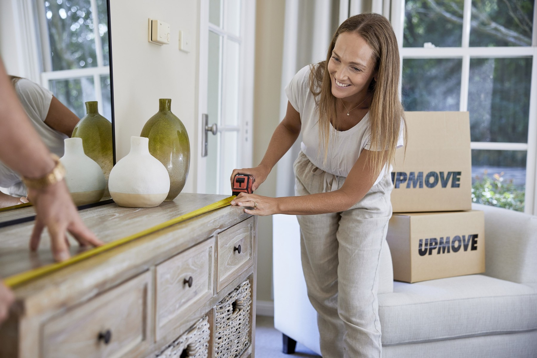 Woman measuring furniture to make sure it fits through entranceway