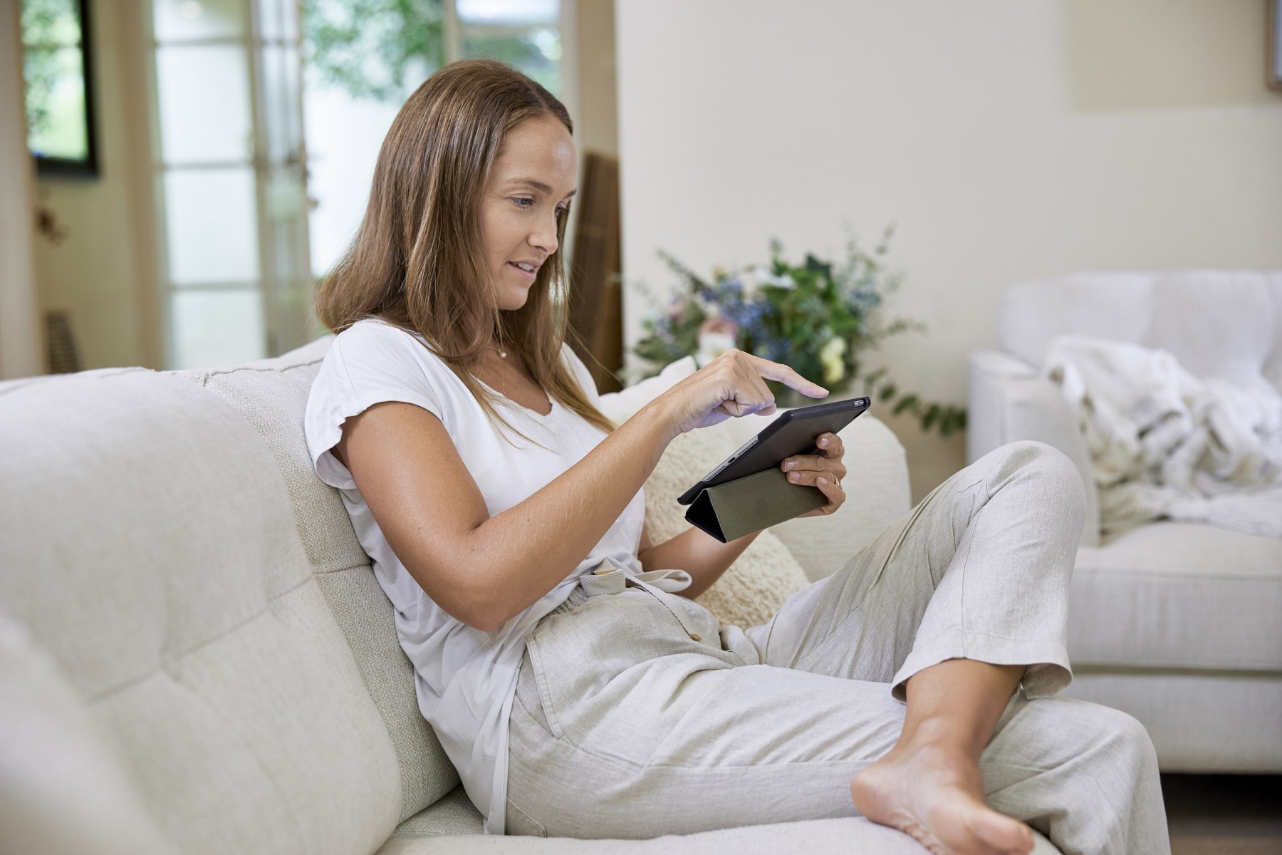 woman sitting on couch looking at tablet