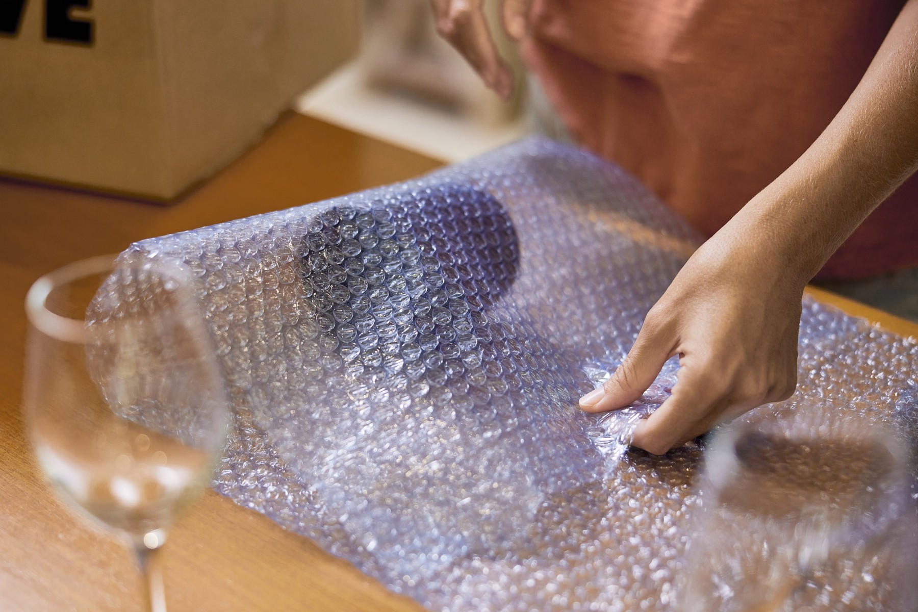 woman wrapping cup in bubble wrap
