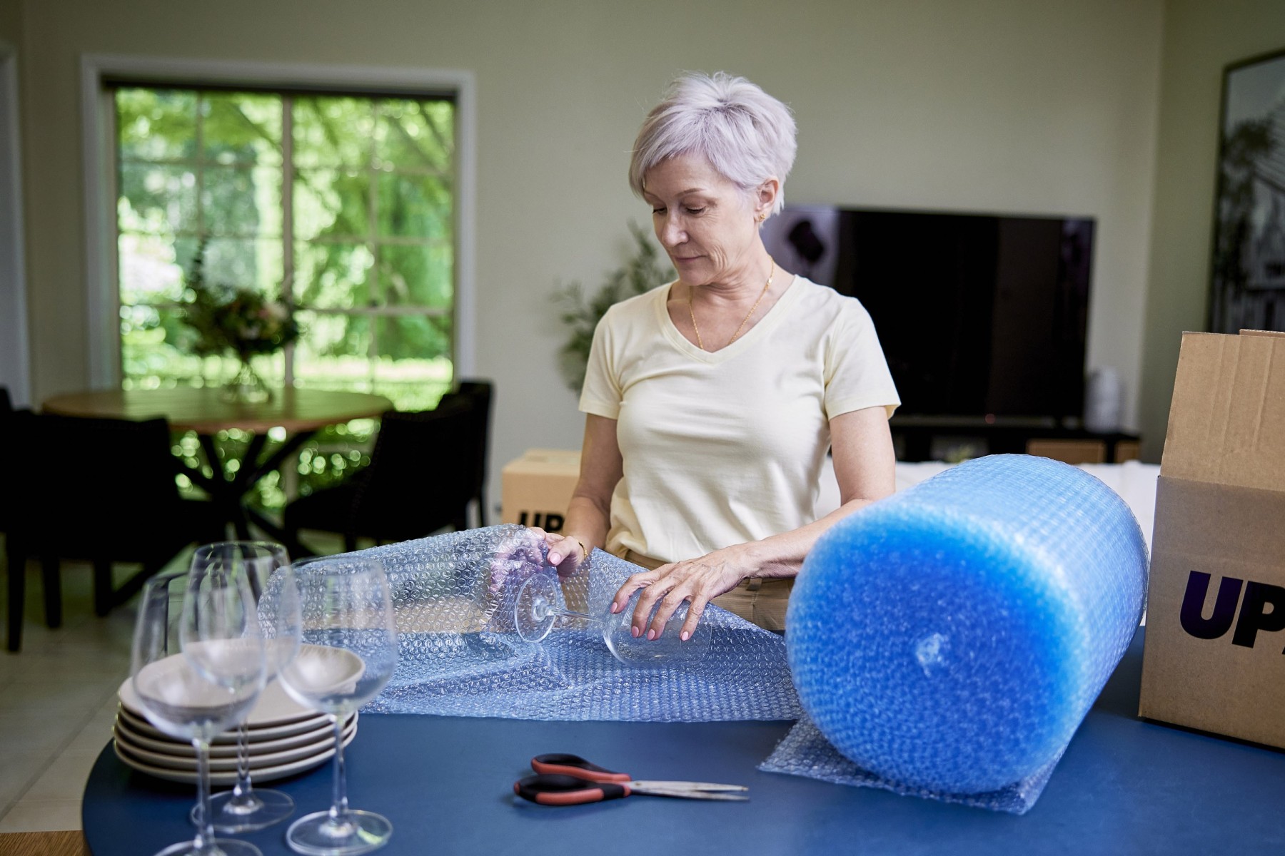 woman wrapping wine glass in bubblewrap