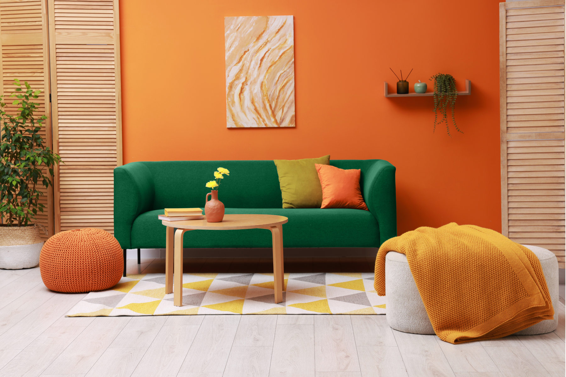 Stylish living room with comfortable green sofa and bright orange wall. Interior design