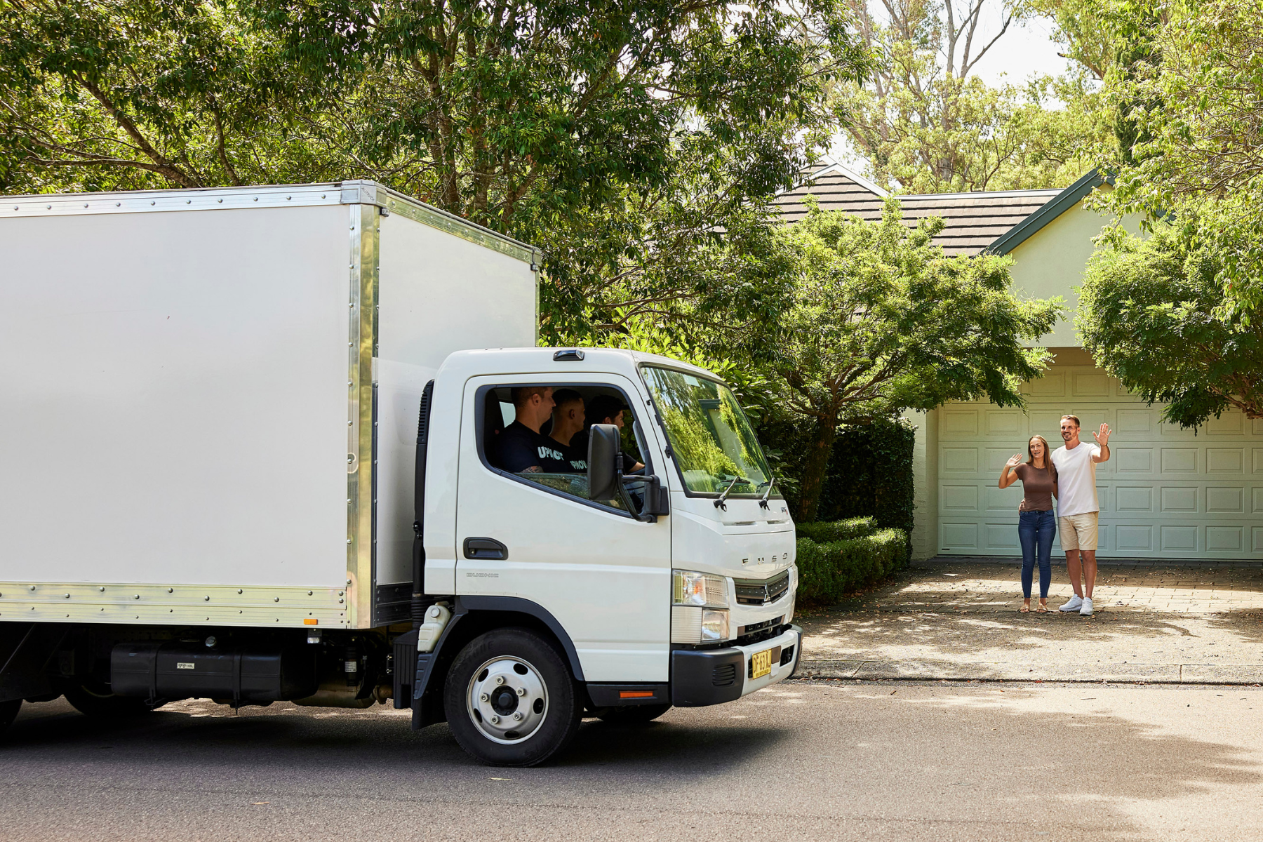 Upmove hard waste removalist truck pulling up to house with couple outside
