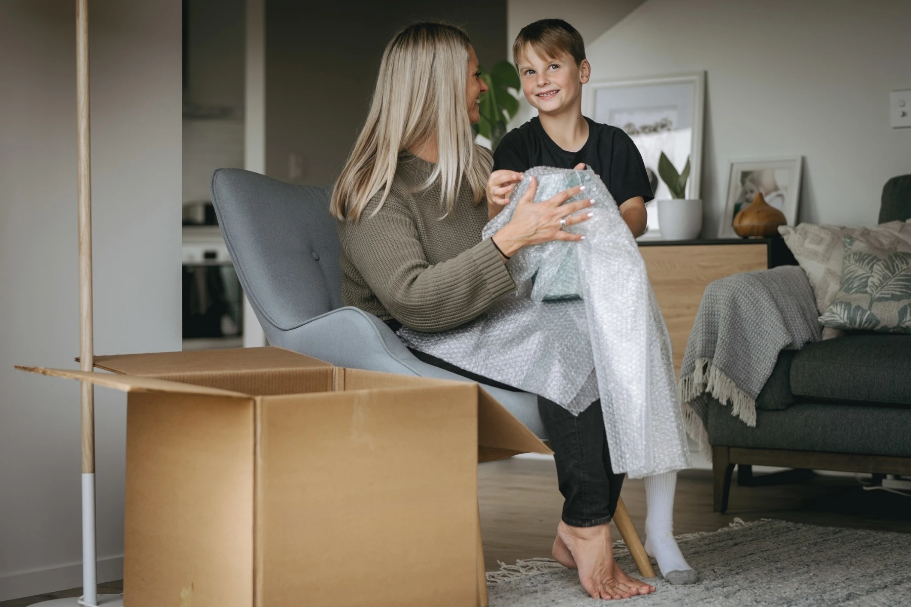 woman and boy wrapping items in bubblewrap