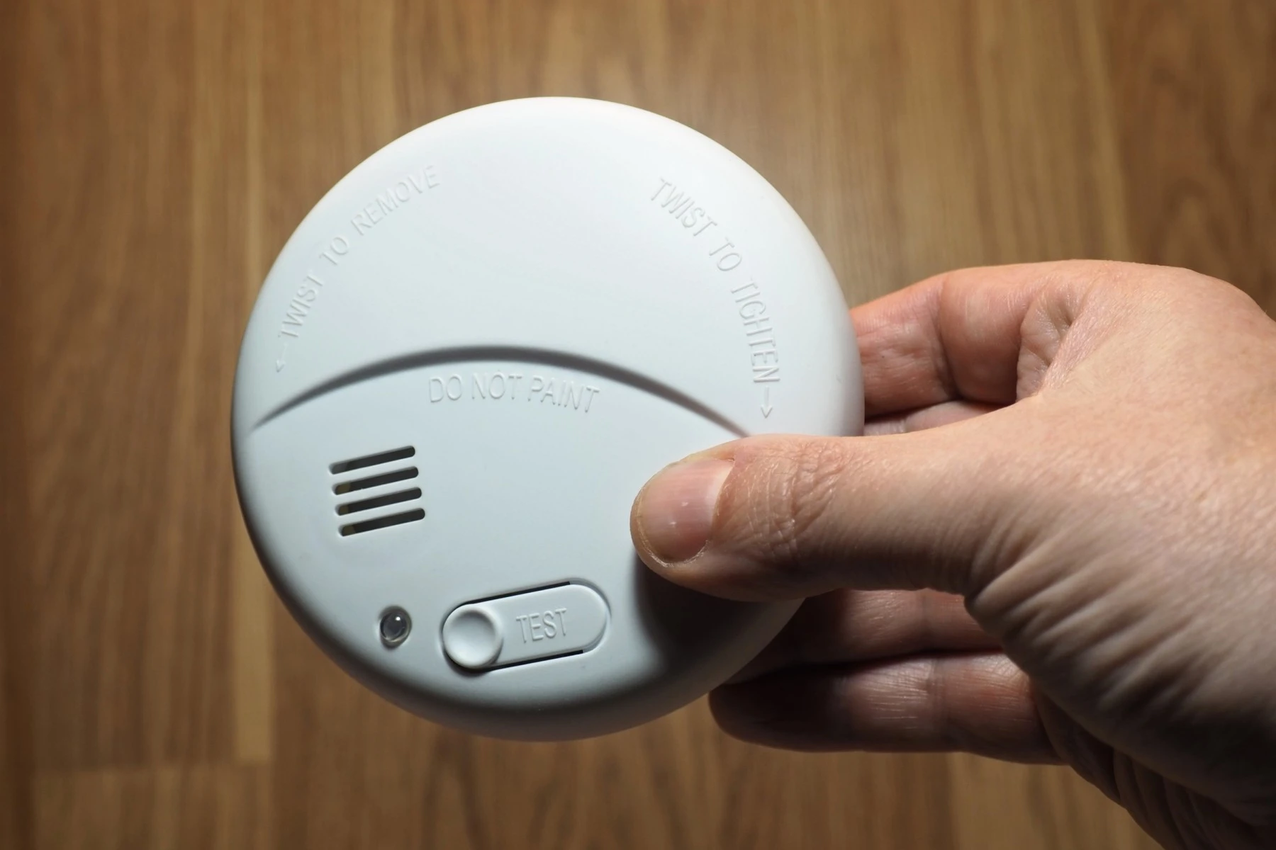 Hand holding a smoke alarm in a Australian home