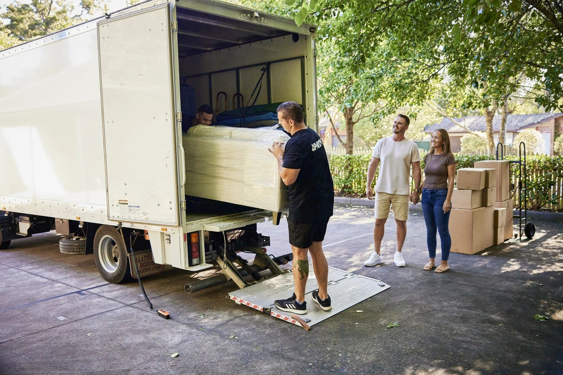 two removalists and couple standing near truck