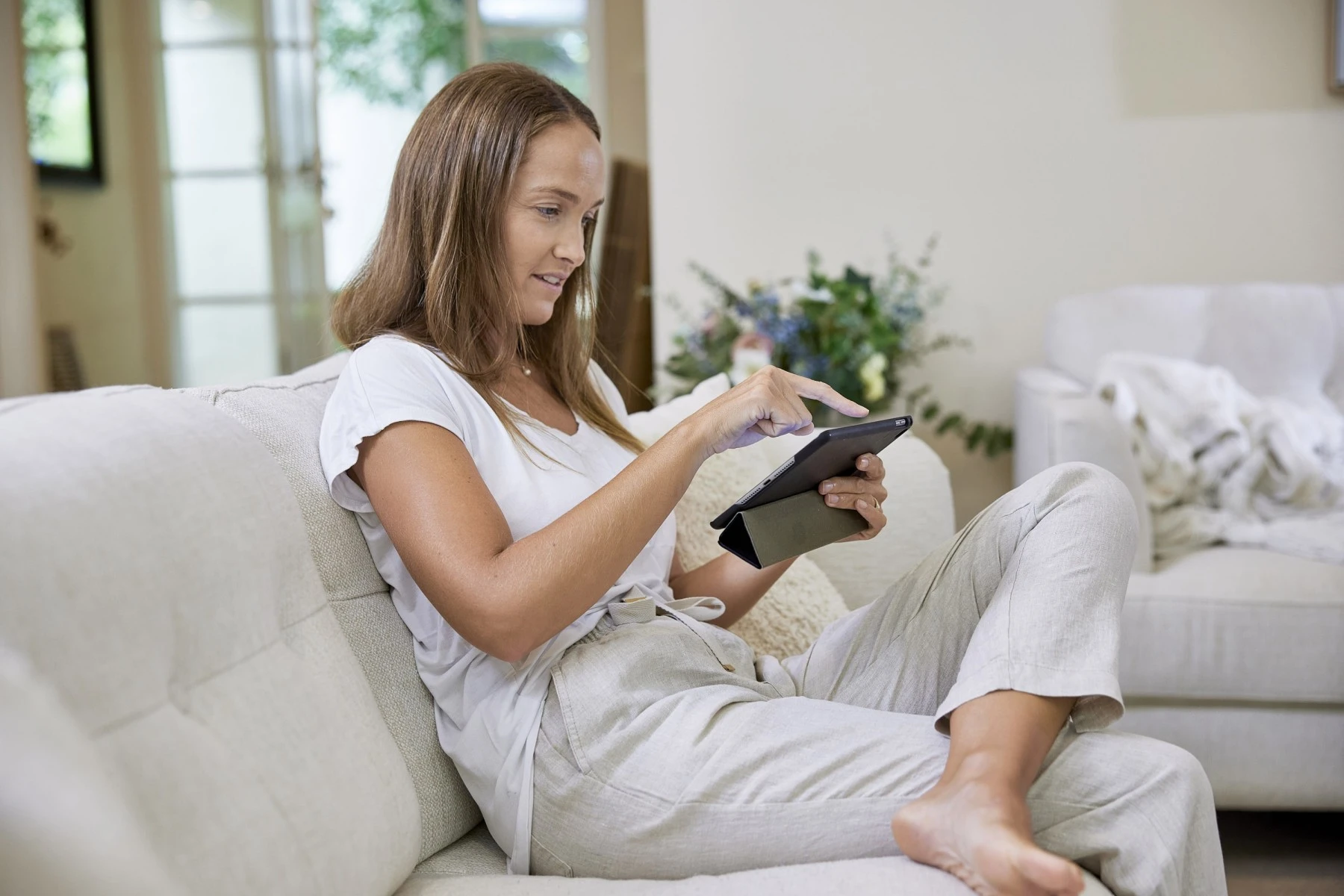 woman sitting on couch looking at tablet