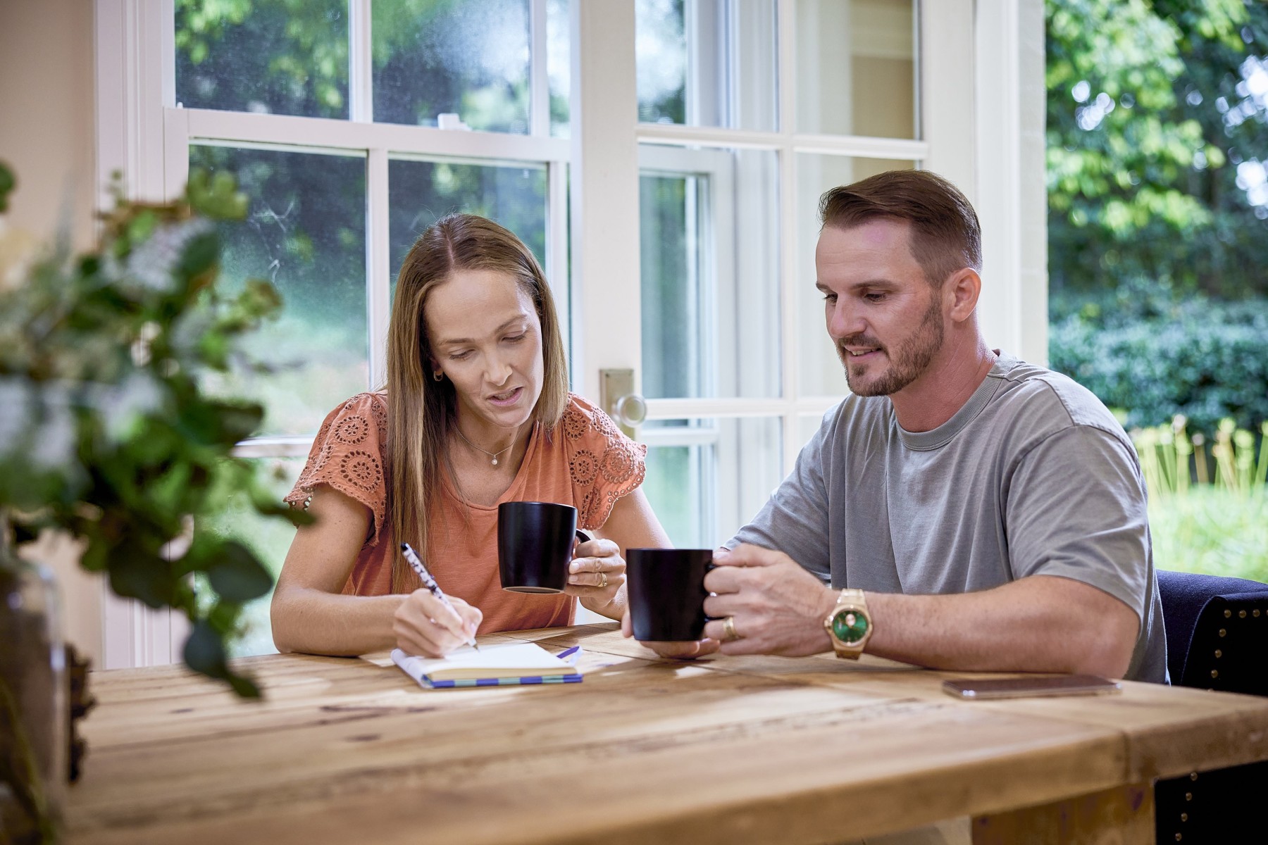 Australian couple making notes at dinner table with tea in hand