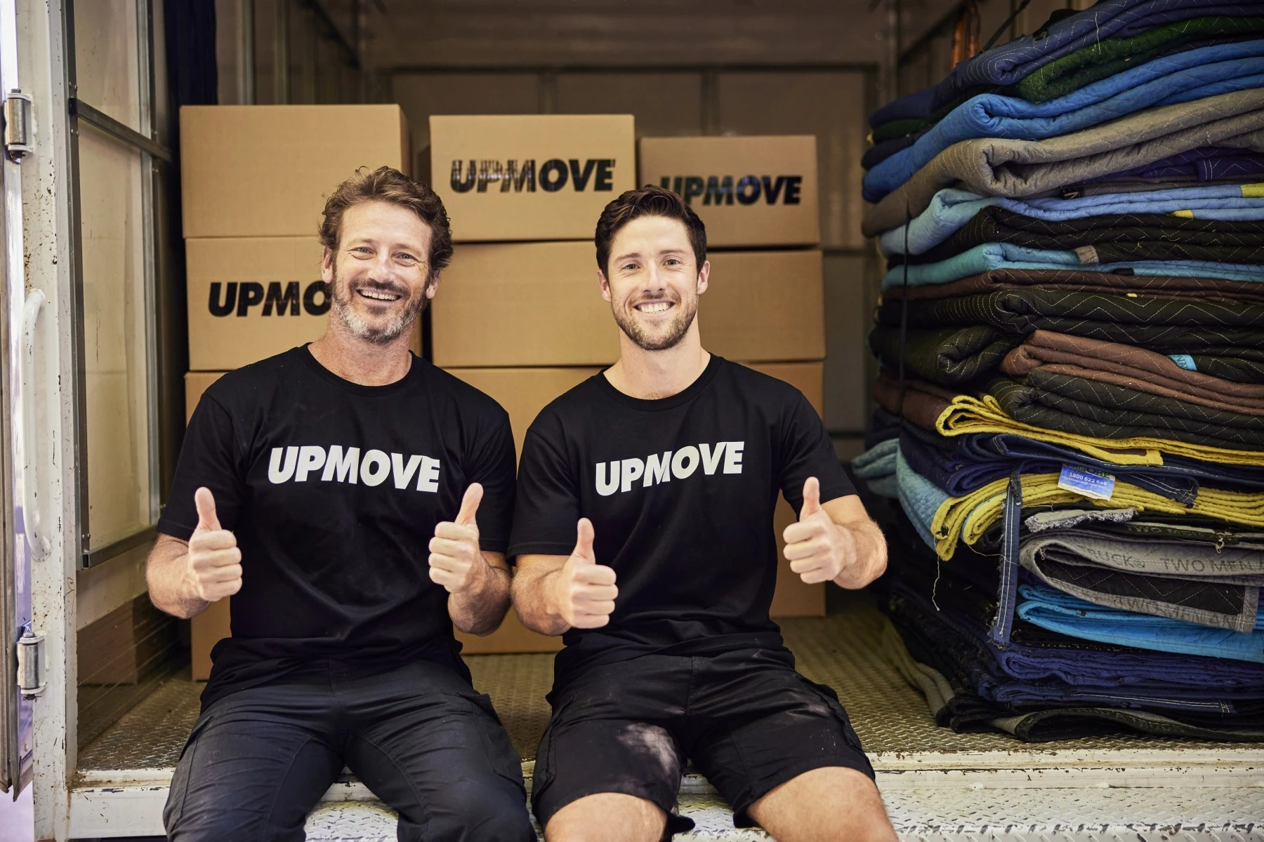 two removalists sitting in the back of a truck