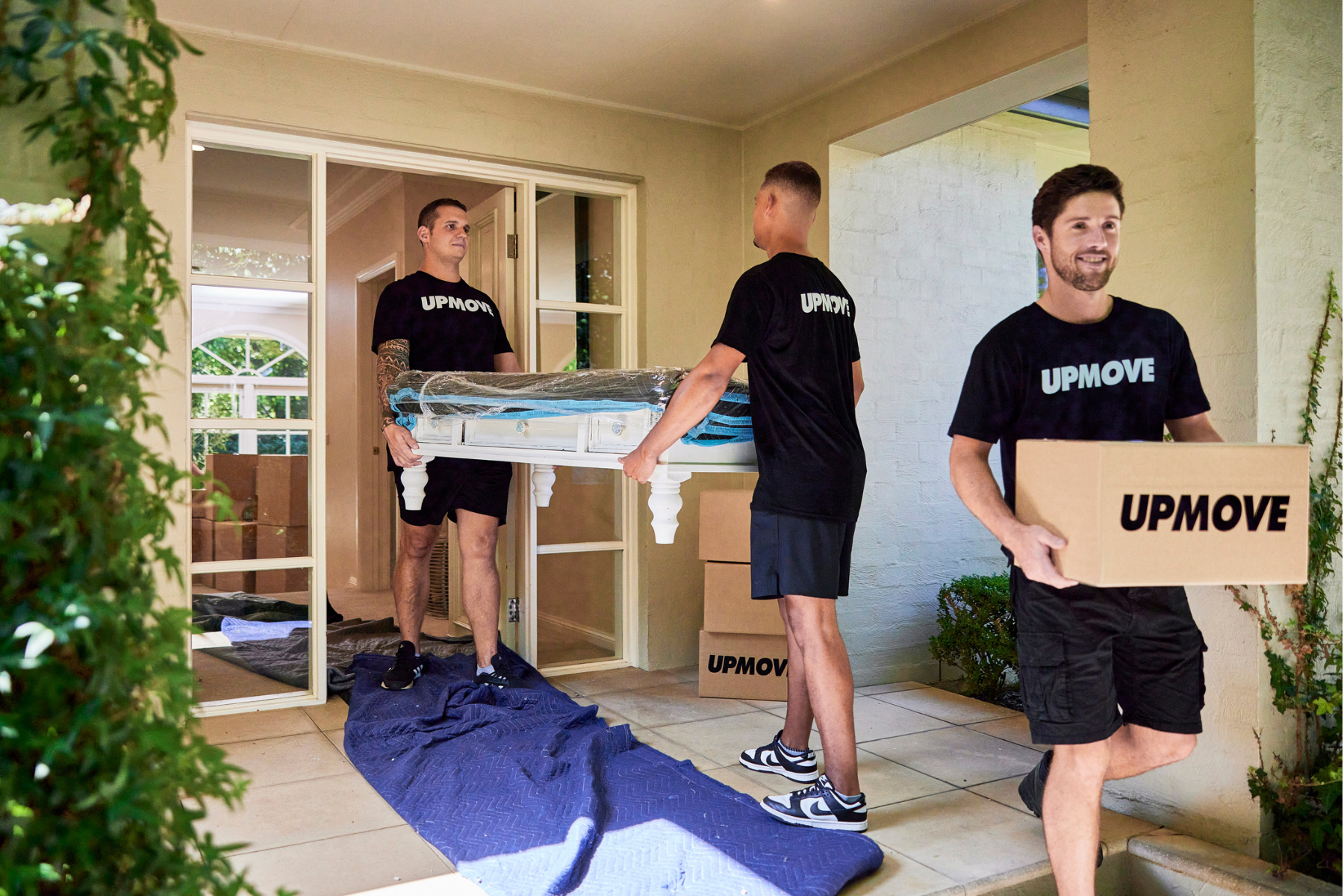 Upmove moving team carrying a coffee table and boxes into a short-term rental home