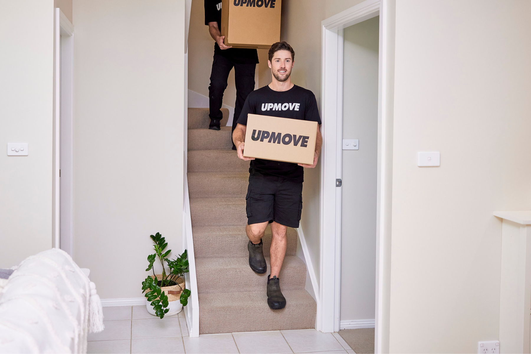 Moving team carrying boxes down stairs in student move