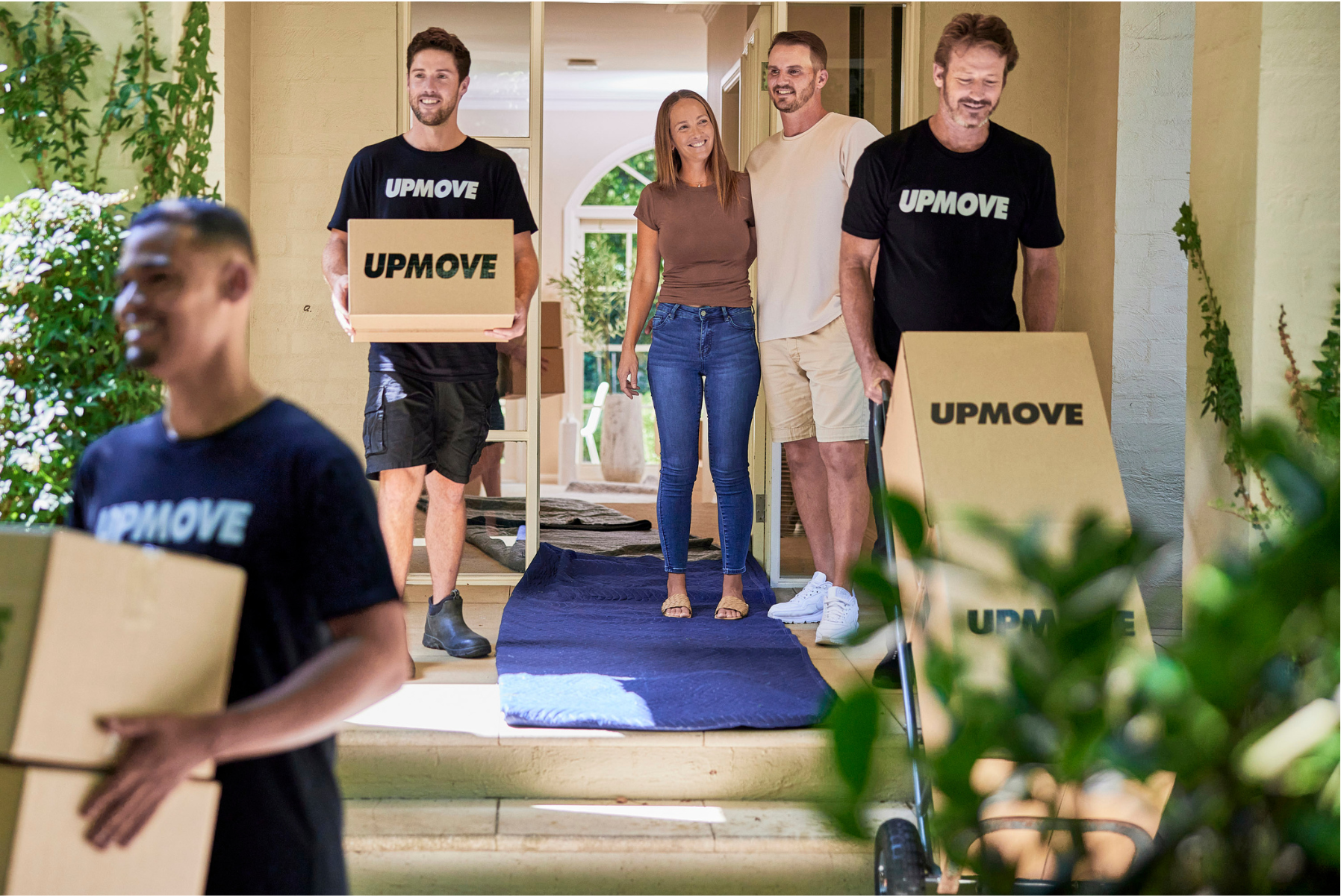 student-friendly moving team carrying boxes out of home for student couple standing by door