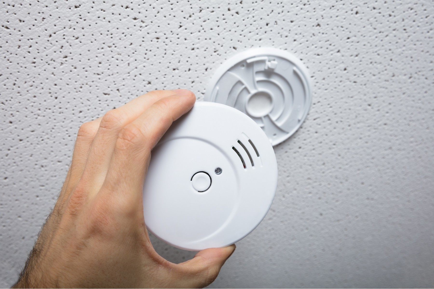 “Electrician testing ceiling smoke alarm in new home