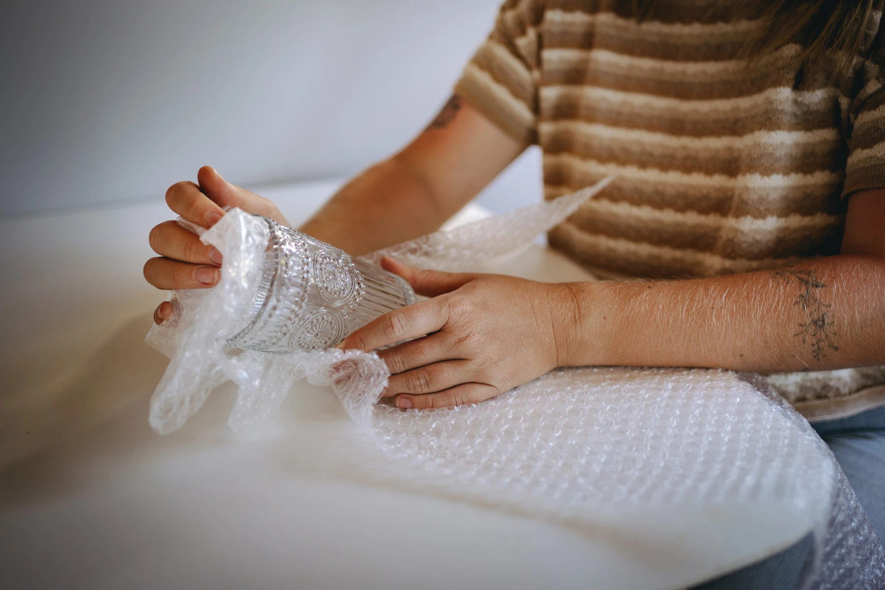 woman wrapping a glass in bubblewrap