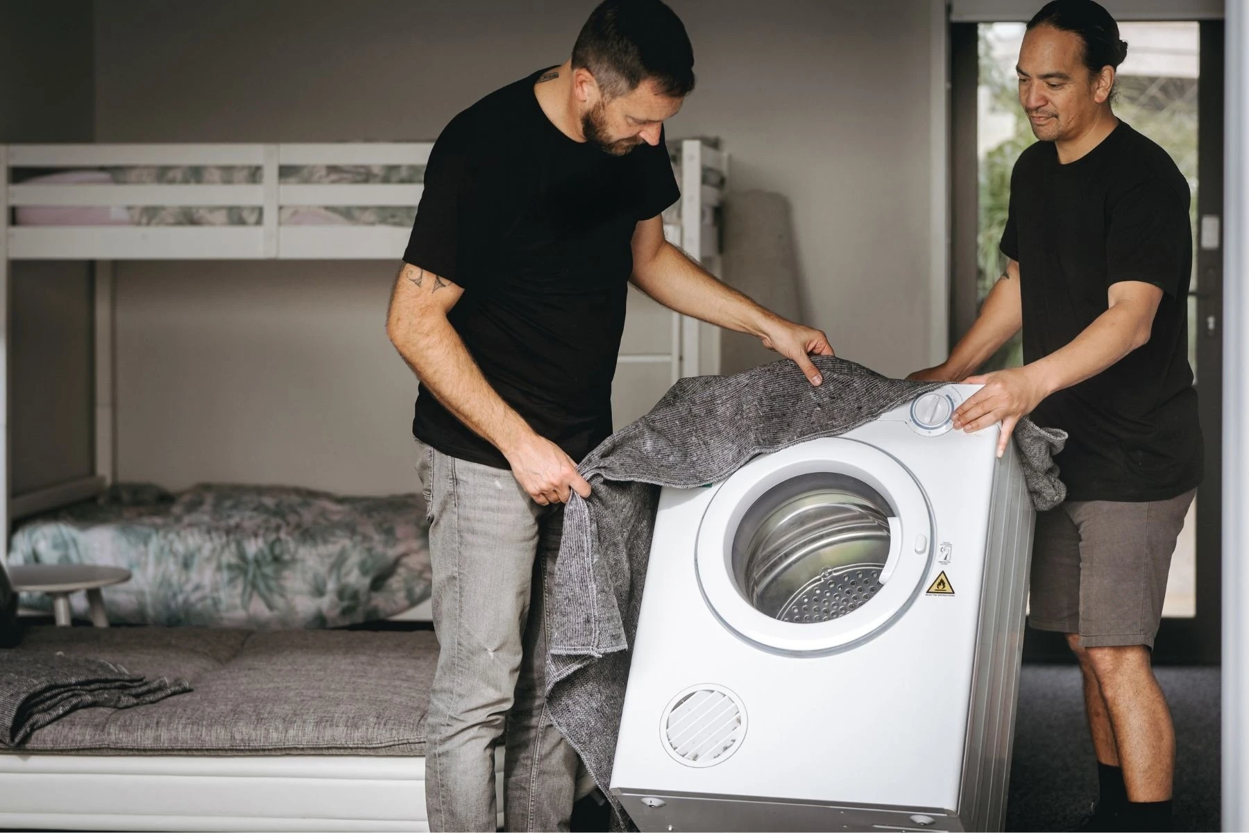 two removalists covering washing machine with blanket